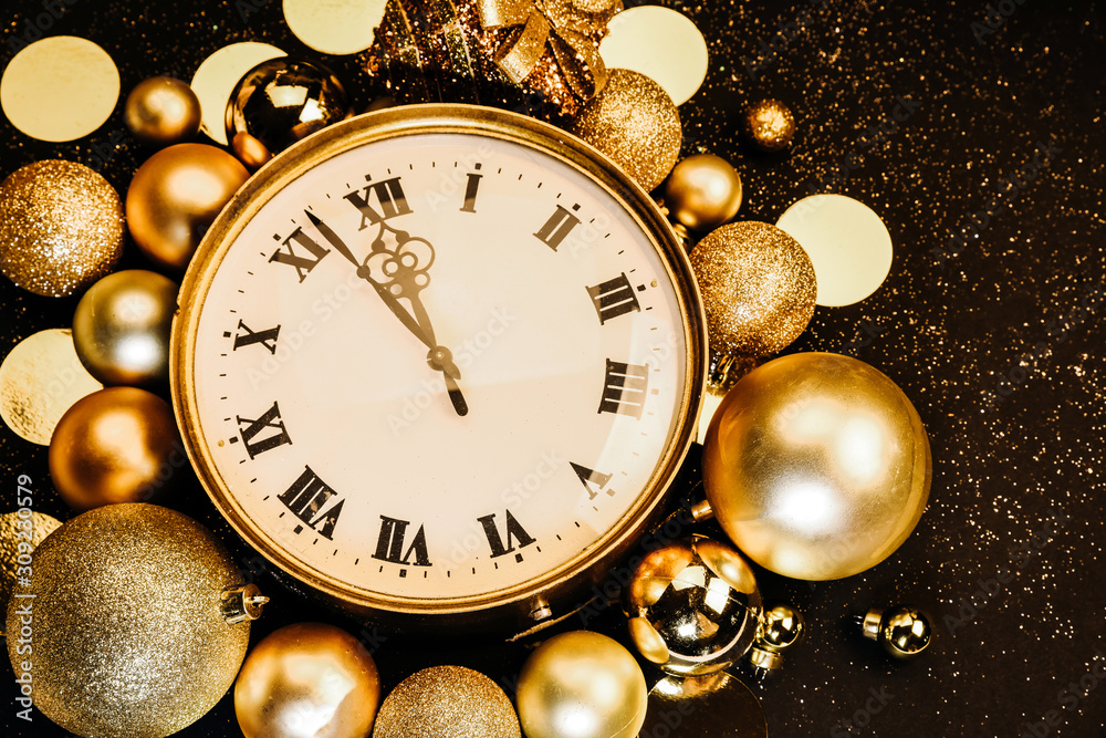 Gold vintage clock decorated with christmas balls on black background sparkles