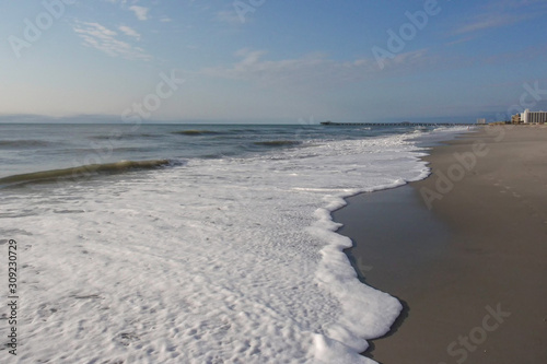 White waves roll up on a beach on a beautiful sunny day