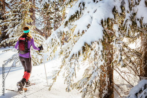 A woman is  hiking wearing snowshoes in Cedar Breaks National Monument.