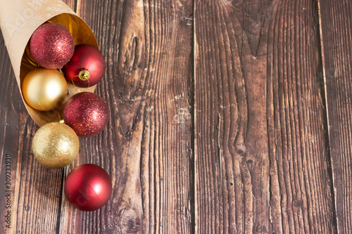 Christmas gifts, gold, silver, red Christmas balls spilled out from a package of kraft paper on a wooden background. Christmas balls. Copyspace.