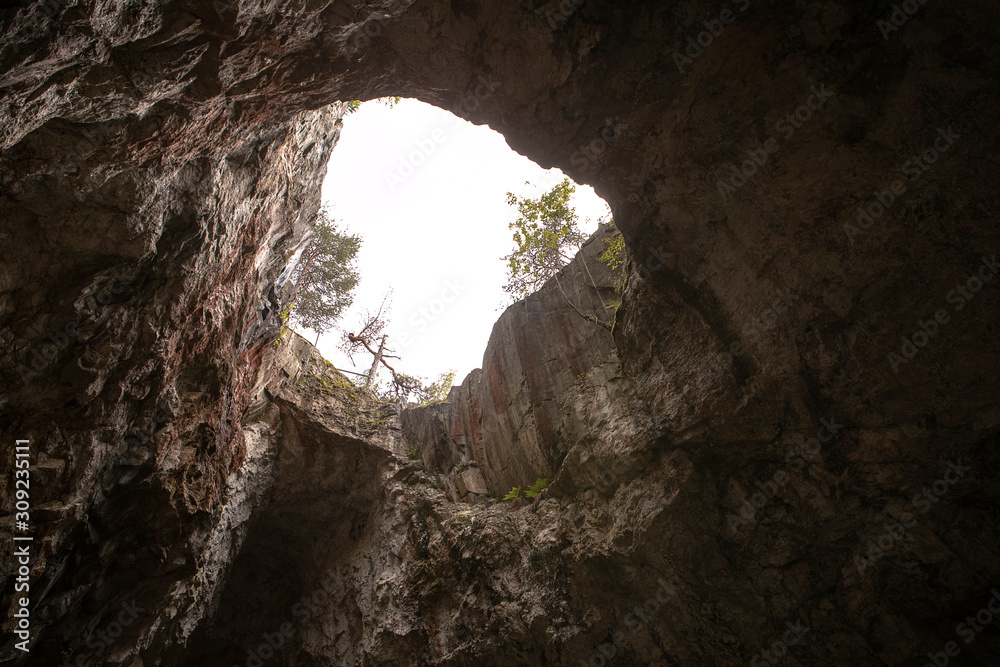 High rocky cave vault. Bright grotto ceiling opening. Light shines through the cave vent. 