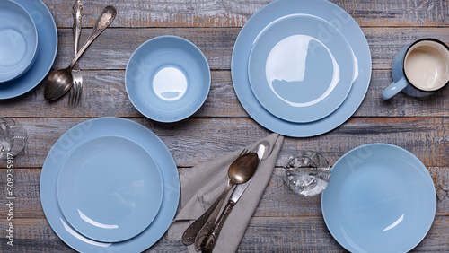 Blue plates, napkin and cutlery on an old gray wooden background.