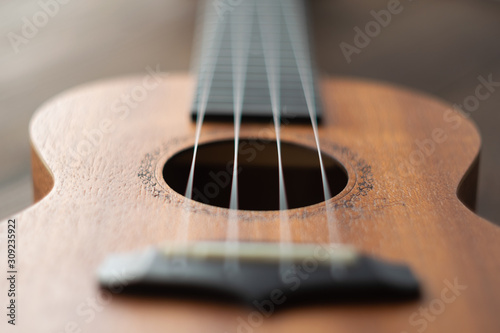 Defocused ukulele strings body, soundhole, bridge and neck on brown wooden background. photo