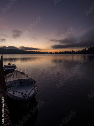A beautiful sunrise at a Lake Bratan with UlunDanu temple Bali Indonesia with traditional fishing boat in foreground. November  2019