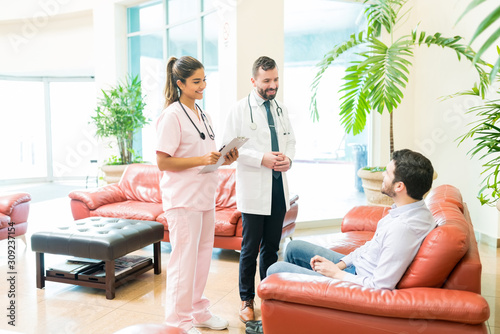 Doctors Speaking To Man In Waiting Room At Hospital