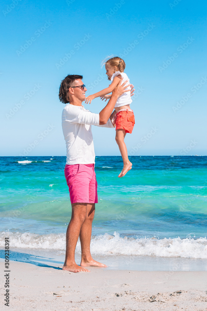 Little girl and happy dad having fun during beach vacation