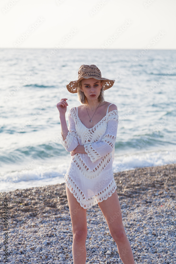 Beautiful fashionable blonde woman on the beach by the ocean