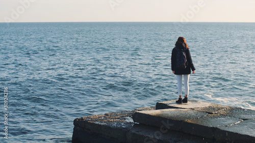 Young beautiful woman walks and enjoys the sea on a warm winter day. Slow motion