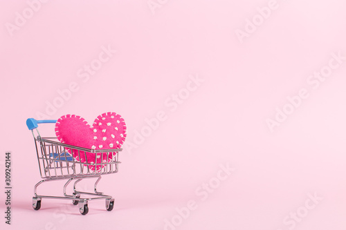 Fototapeta Red heart as a symbol of love, in a shopping trolley, the concept of buying heart for money for Valentine's Day