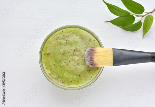 Kiwi fruit facial mask, cosmetic brush, natural acne treatment, top view.