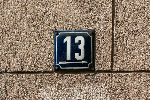 Weathered grunge square metal enameled plate of number of street address with number 13 closeup photo