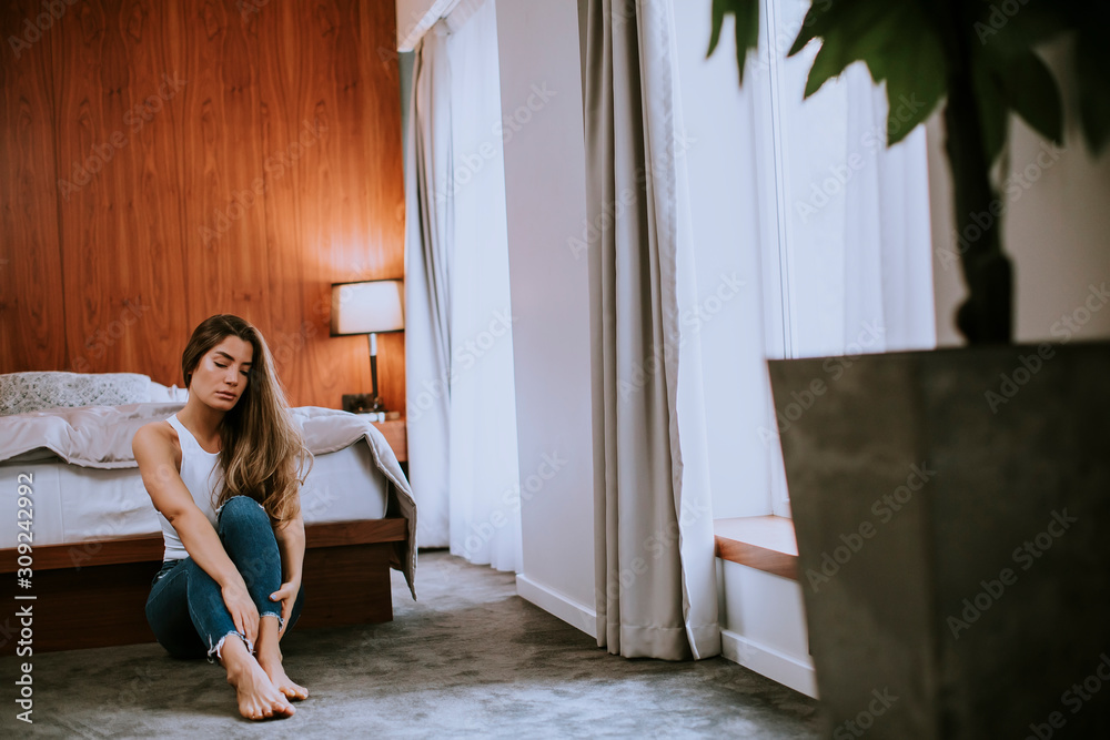 Attractive young woman sitting on the floor in the bedroom at home Attractive young woman sitting on the floor in the bedroom at home