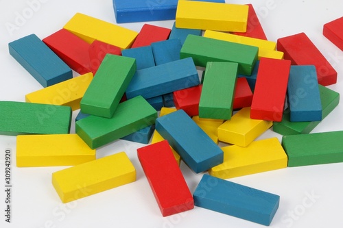 heap of colorful wooden building blocks are lying in a white studio