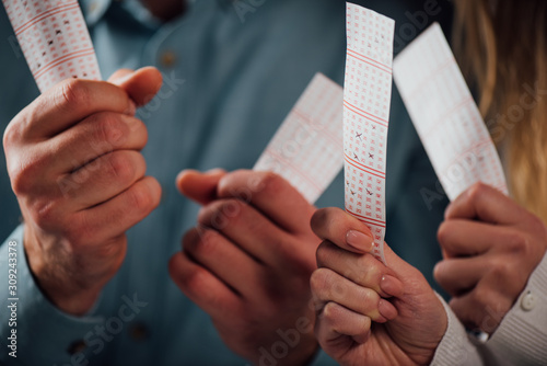 cropped view of man and woman holding lottery tickets while waiting for lottery results photo