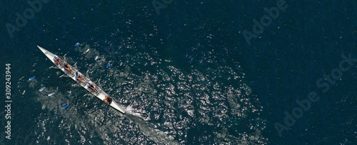 Aerial drone ultra wide photo of team of fit women practising in sport canoe in deep blue open ocean sea