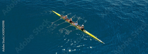 Aerial drone ultra wide photo of team of fit women practising in sport canoe in deep blue open ocean sea