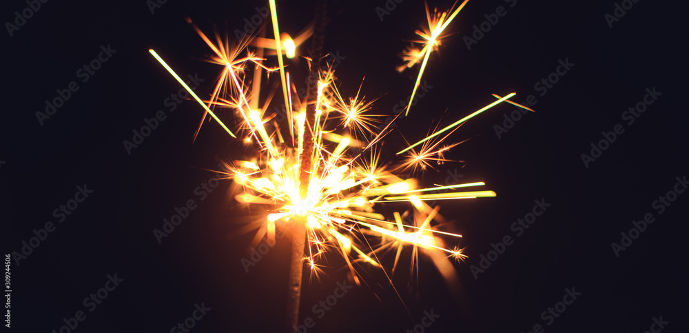 Bright sparklers for Christmas and New Year close-up in the form of a banner and on a black background