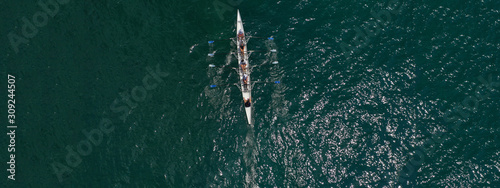 Aerial drone ultra wide photo of team of fit women practising in sport canoe in deep blue open ocean sea © aerial-drone
