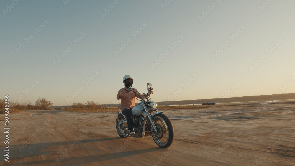 Fototapeta premium Motorcyclist driving his motorcycle on the dirt road during sunset