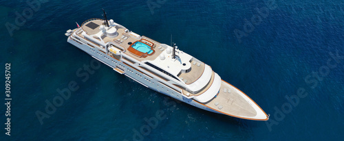Aerial drone ultra wide photo of luxury mega yacht with wooden deck docked in Aegean island destination deep blue open sea © aerial-drone