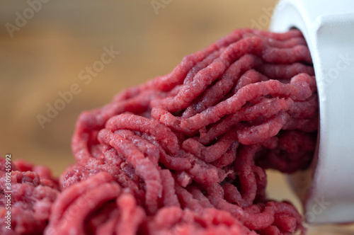 Cook makes minced fresh meat in a meat grinder