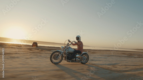 Motorcyclist driving his motorcycle on the dirt road during sunset