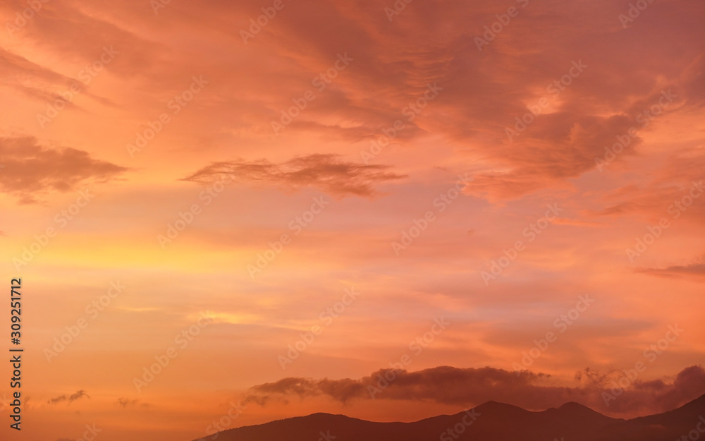 Calm orange and pink sunset sky, silhouettes of mountains below - can be used as background with subjects placed in front