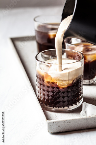 Close up of milk pouring over iced coffee photo