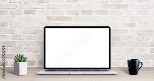 Laptop mockup on simple, clean desk with brick wall in background. Isolated screen for ap, web site resentation. Plant and cup of coffee on table photo