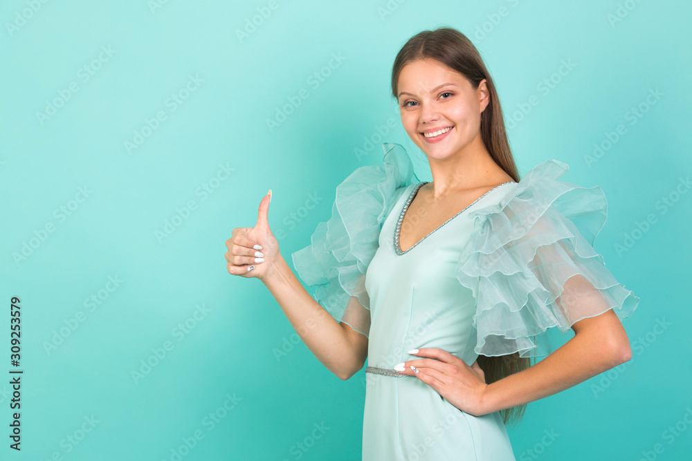 beautiful young woman in a blue dress on a blue background with hand gesture beautiful young woman in a blue dress on a blue background with hand gesture
