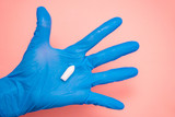 White suppository for anal or vaginal use in hand of a doctor wearing gloves on a pink background. Medical candles for treatment of Candida, thrush, hemorrhoids, inflammation and fever. Copy space
