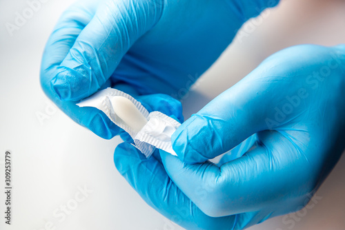 A gloved doctor opens suppositories for anal or vaginal use. Medical candles for the treatment of Candida, thrush, hemorrhoids, inflammation and fever. Effective drug on a white background