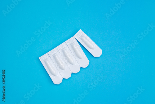 White suppositories for anal or vaginal use on blue background. Medical candles for treatment of Candida  thrush  hemorrhoids  inflammation and fever. Effective drug for timely treatment of diseases