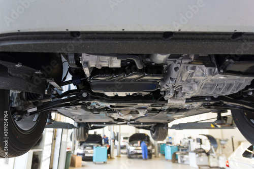 Car repair in a car service. View of the car from below against the background of the interior of a car service.