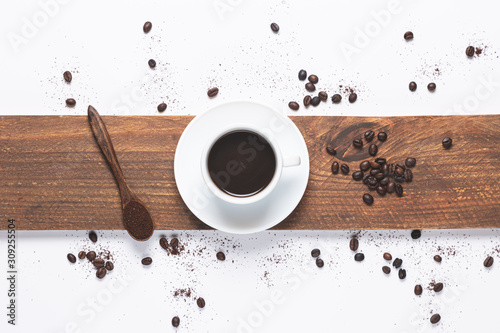 white coffee cup , coffee beans spilled, wooden spoon with coffe on white background. Top view.
