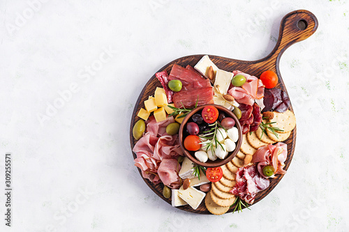 Fotografie Antipasto platter with ham, prosciutto, salami, cheese,  crackers and olives on a light background
