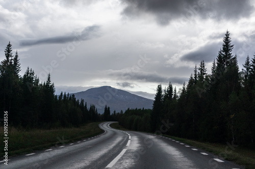 Dramatic northern scandinavian route. Cold northern europe freeway. Nature forest, mountains road perspective view. Travel scenery.