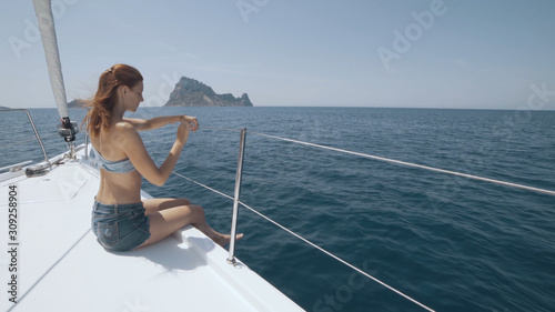 Beautiful woman on a yacht enjoys the journey on the background of the islands of Ibiza or Mallorca. Luxury yacht near the balearic islands © tol_u4f