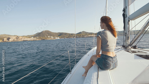 Beautiful woman on a yacht enjoys the journey on the background of the islands of Ibiza or Mallorca. Luxury yacht near the balearic islands