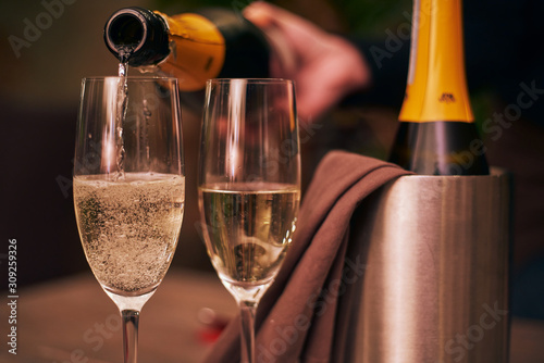 Close up shot of pouring champagne into two glasses