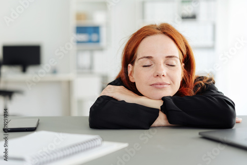 Serene young woman closing her eyes at the office