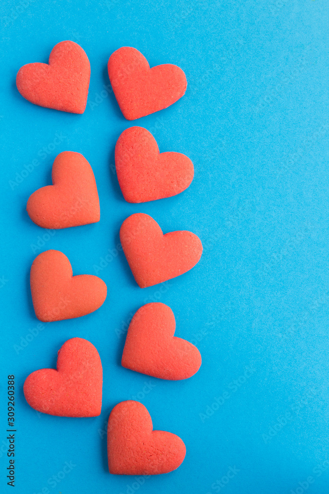 Red hearts shaped cookies on the blue background. Copy space. Top view. Location vertical.