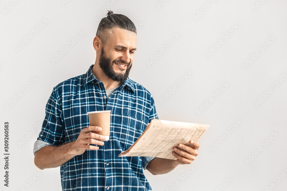 Freestyle. Guy in checkered shirt standing isolated on white reading newspaper drinking hot coffee smiling joyful copy space Freestyle. Guy in checkered shirt standing isolated on white reading newspaper drinking hot coffee smiling joyful copy space