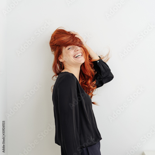 Laughing vivacious woman tousling her hair photo