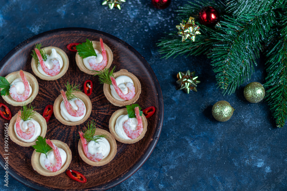 Tartlets with cream cheese and shrimp. Decorated with sprigs of dill and parsley. Seafood.