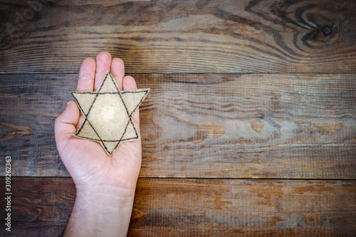 Male hand and star of David on a wooden board background. Holocaust Remembrance Day photo