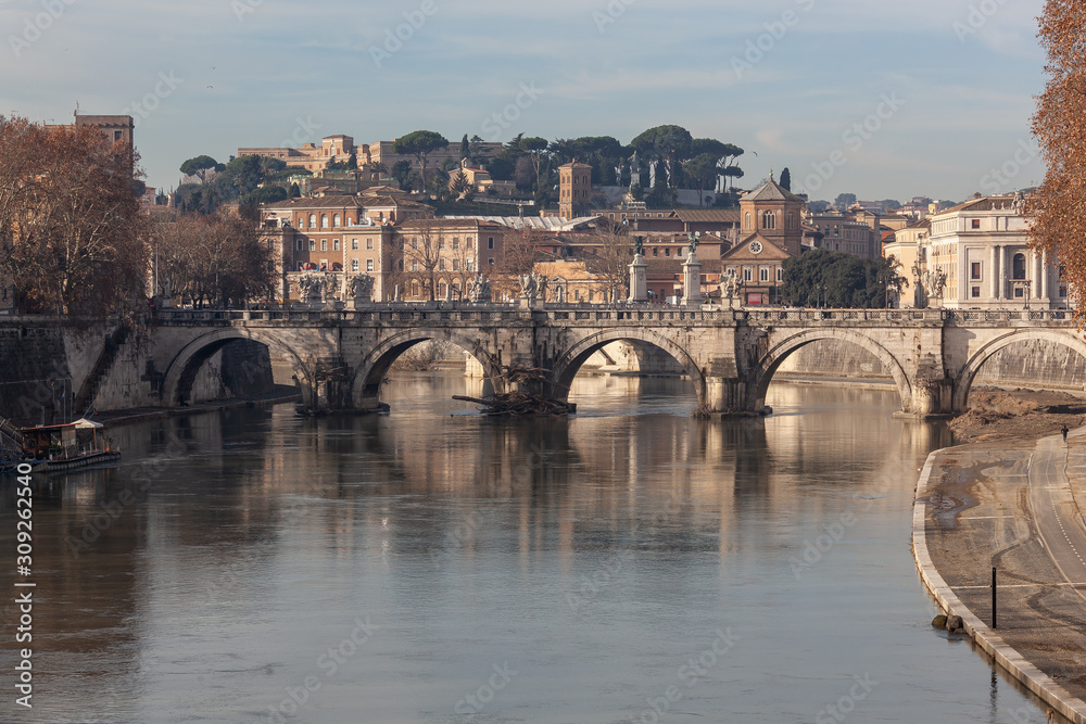 Ancient Sant'Angelo Bridge through the Tiber River in Rome in sunny winter morning, Italy