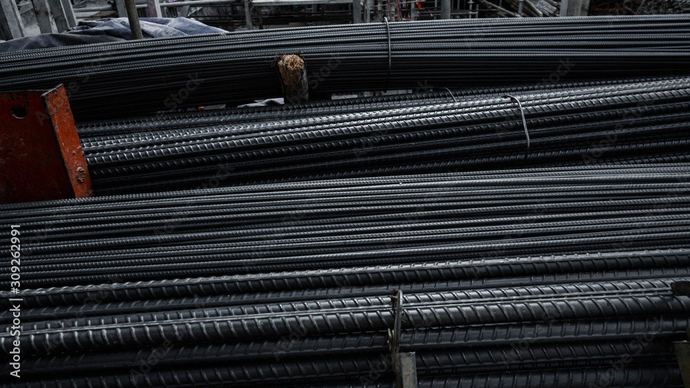 Obraz premium Building armature in the warehouse of metallurgical products or on construction site. Stack of heavy metal reinforcement bars with periodic profile texture. Steel construction armature.