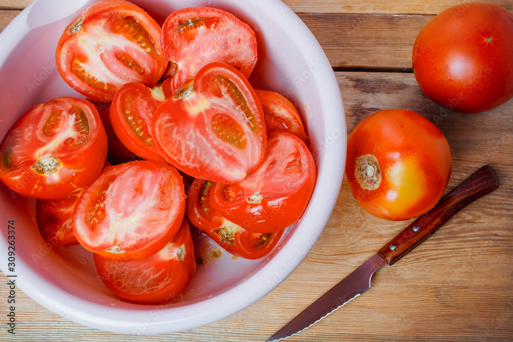 Tomato slices in a bowl on a wooden background Tomato slices in a bowl on a wooden background