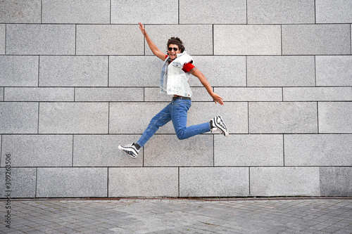 Young adult man jumping against city wall